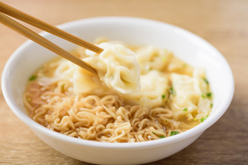 Instant noodles soup and wonton dumpling stuffed with minced pork in a bowl eating by chopsticks, Asian food