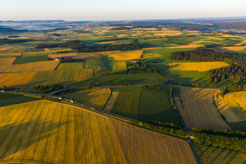 Aerial view of beautiful countryside at sunset; green fields and farmlands