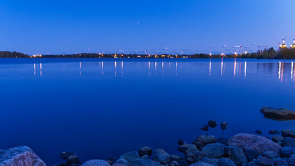 Blue sky and lake; night lights reflecting on the lake