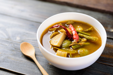 Southern Thai food (Kaeng Tai Pla ), fish organs sour soup in a bowl and spoon on wooden background