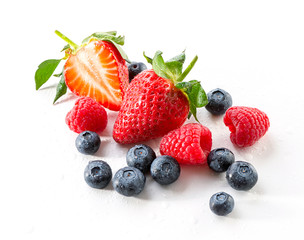 set of fresh garden berries  strawberries, raspberries and blueberries close-up sprinkled with water drops on white background