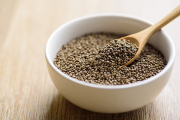 Organic perilla seeds in a bowl with spoon on wooden background, healthy herbal seed ingredient in Asian food