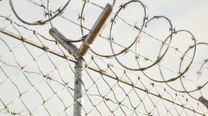 Endless view at the top of prison or airport fence on blue sky background. 4k HD