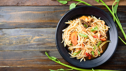 Thai food (Som Tum), spicy green papaya salad on wooden background, Top view