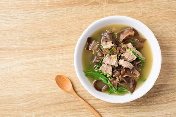 Spicy brown jelly mushroom soup with pork in a bowl on wooden table, Local Thai food, Top view