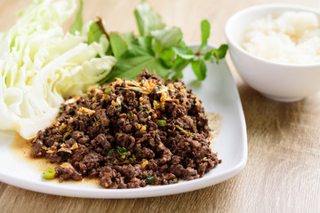 Local Northern Thai food, spicy minced pork salad (Larb Moo Kua) eating with fresh vegetables and sticky rice