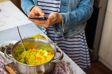 Woman take picture of food with phone at kitchen or summer cafe. Smartphone photography of vegetables dinner or lunch for blogging or social media publications. Vegan vegetarian healthy diet.