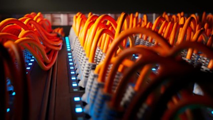 Countless orange cables in a  server cabinet lit by a single spotlight. 4KHD