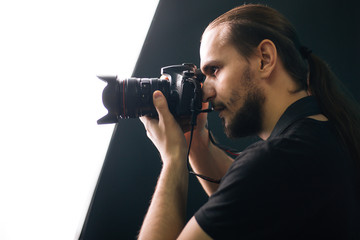 A photographer in a black T-shirt is holding a camera. The guy in the dark. Silhouette