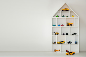 Toy racing car storage. Beautiful white house shelf for toys. Boyhood. Childhood. concept with copy...