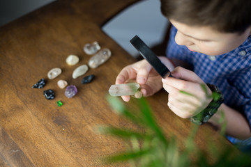 A cute kid studying semi precious stones on a rustic table background