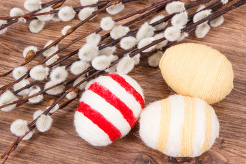 Twigs of willow and colorful Easter eggs wrapped woolen string on rustic board
