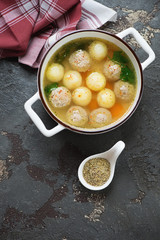 Meatball and potato soup in a white bowl, flatlay on a brown stone background with space, studio shot