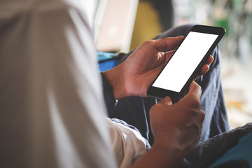 Cropped shot view of man hands holding smart phone with blank copy space screen for your text message or information content, female reading text message on cell telephone during in urban setting.