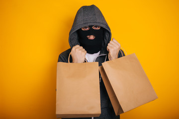 Thief with paper bags. The guy in the balaclava steals purchases from the store. Masked man on...