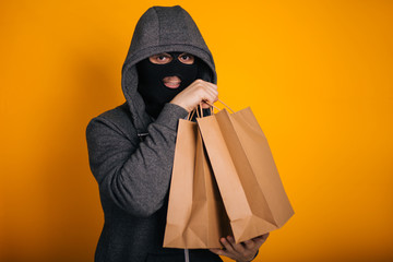 Thief with paper bags. The guy in the balaclava steals purchases from the store. Masked man on...