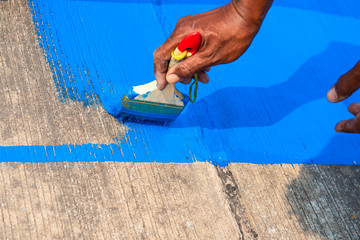The painter is painting the traffic sign on the concrete road