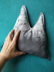 Mountain range, gray throw pillow on blue background, gift to climber traveler. Hand holds pillow.