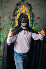 A guy in a black mask in the form of a skull and in a black cloak. Evil sorcerer with a magic wand....