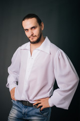 A guy with a beard in a white vintage shirt. Romantic portrait on a gray background