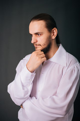 A guy with a beard in a white vintage shirt. Romantic portrait on a gray background