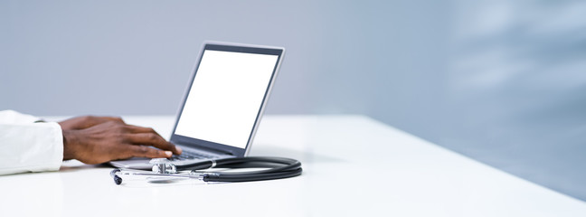 Midsection Of Doctor Using Laptop At Desk