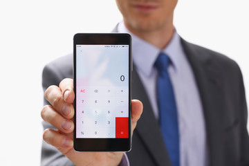 A businessman holding smartphone in hand demonstrates display on which calculator is depicted with figure of zero. The accountant has calculated all transactions are correct debt has credit approx ok