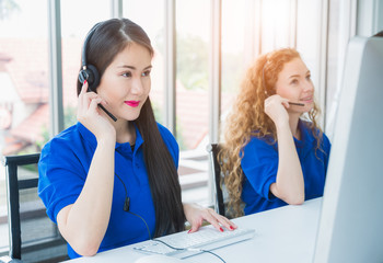 Asian female customer support operator at work. Team Business and Delivery call center in office. Working with a headset in blue uniform.