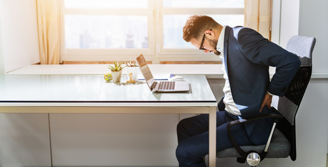 Businessman Sitting On Chair Suffering From Back Pain