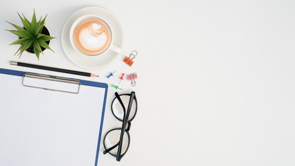 Panoramic work space business office table desk with blank note and coffee cup, glasses and paper clip, green plant, Top view with copy space 