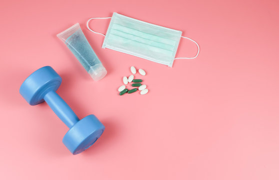 Hand Sanitizer , Disposable Hygienic Mask,medical pill or vitamin and dumbell on pink background with copy space . protection against pm2.5 and COVID-19 concept. © Phuttharak