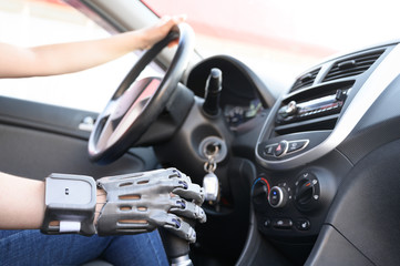 A person with a prosthetic hand printed on a 3d printer drives a car. Concept of practical application of 3D printing.