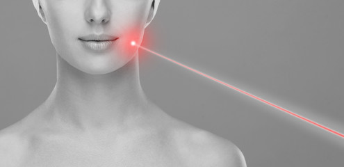 Doctor removing birthmarks with a laser ray. Beautiful face of a young woman. Mole removal, plastic...