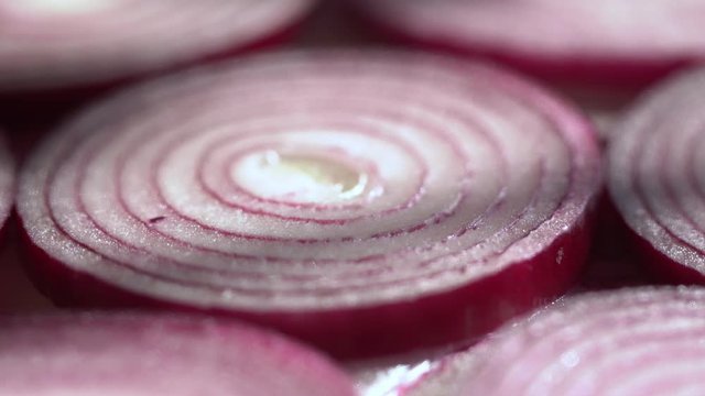 Sliced red onion rings rotating on white in 4K. Closeup top view of healthy food background with vegetable of rich vitamin.