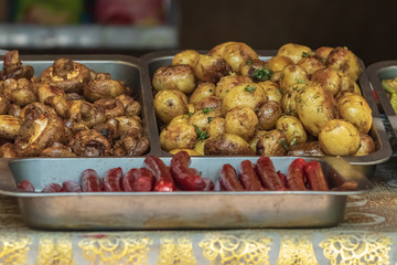 Culinary buffet with the presentation of healthy food - mushrooms, potatoes, sausages, peppers, spices, grilled vegetables. Food market, festival, event. The kitchen is outdoors. Street fair stand.