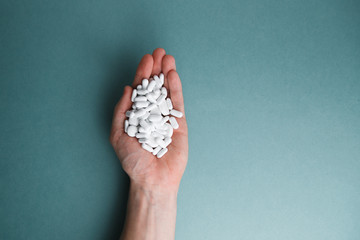 White tablets on a blue background are isolated. Hand with a tablet. A pile of pills in the open palm. Virus protection and 2019-ncov.