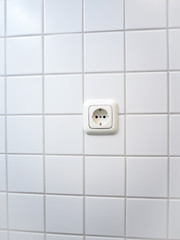 one socket on the white tile in the bathroom