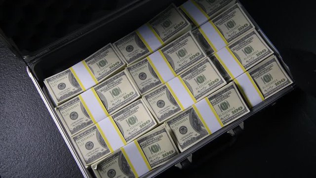 Briefcase full of money with packs of narcotic drugs hidden underneath .