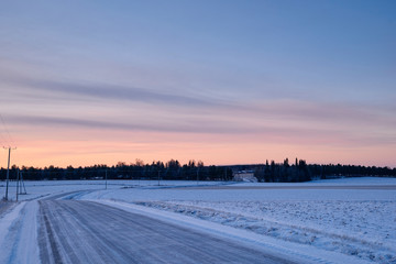 Icy road in the morning in countryside with some trees in the background