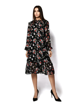 Young brunette woman model with long straight hair is in relaxed pose in stylish vintage dark dress with flower print