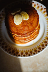 Close-up delicious pancakes, decorated with banana and honey. Black background.