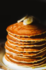 Close-up delicious pancakes, decorated with banana and honey. Black background.
