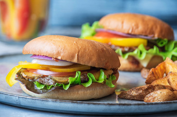 freshly cooked homemade beef burgers and crunchy potatoes on gray plate, no people