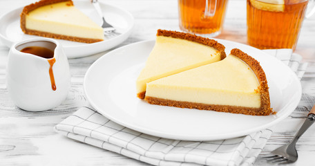Cheesecake slices with caramel sauce on white plate. Slices of classic cheesecake. 