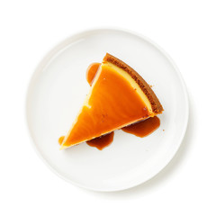 Cheesecake slice with caramel sauce on white plate isolated on white background