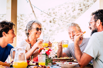 Happy and cheerful mixed ages and generations caucasian family stay together eating at lunch at home or restaurant - people enjoy fathers and son celebration