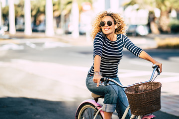 Beautiful and cheerful adult young woman enjoy bike ride in sunny urban outdoor leisure activity in...