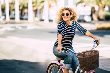 Fotobehang Beautiful and cheerful adult young woman enjoy bike ride in sunny urban outdoor leisure activity in the city - happy people portrait - trendy female outside having fun © simona