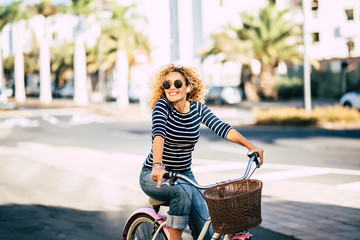 Beautiful and cheerful adult young woman enjoy bike ride in sunny urban outdoor leisure activity in the city - happy people portrait - trendy female outside having fun