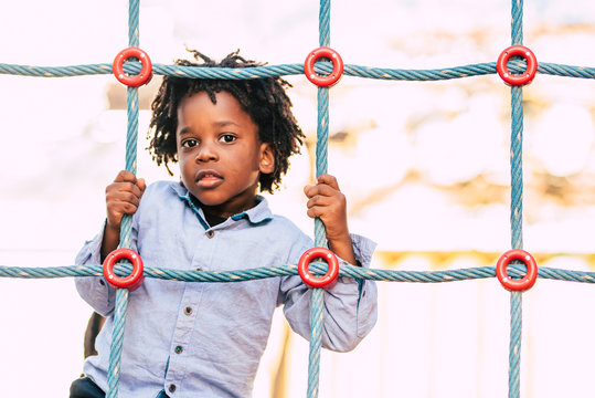 Happy And Beautiful Young Kid Black Race African With Ethnic Alternative Hair Playing In A Playground With Coloured Cords And Have Fun